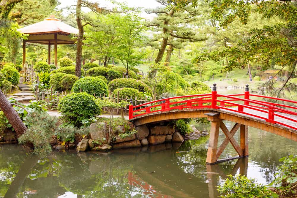 Shukkeien Garden in Hiroshima with a red Bridge over a pond.