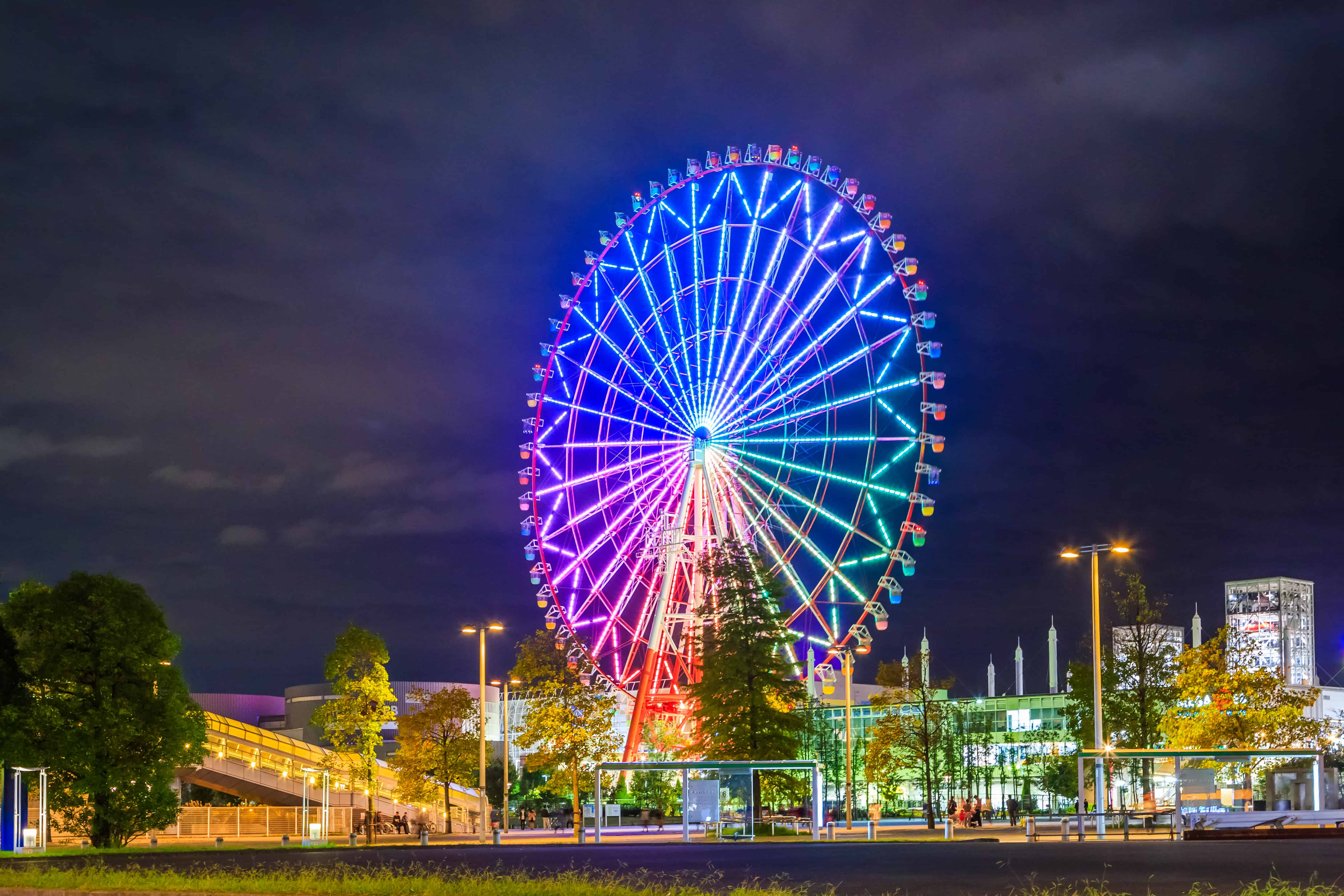 Odaiba,Tokyo at night with the Ferris wheel lit up with vibrant colors of green, blue, yellow, and red.