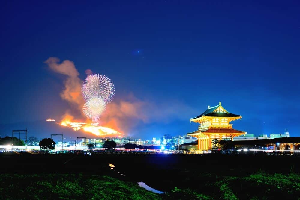 Mt. Wakakusa-Yama. Fireworks can be seen in the sky and a lit up temple building on the right side.