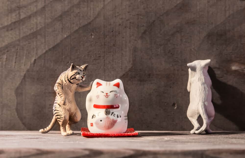 Small Japanese style cat figurines on a wooden surface.