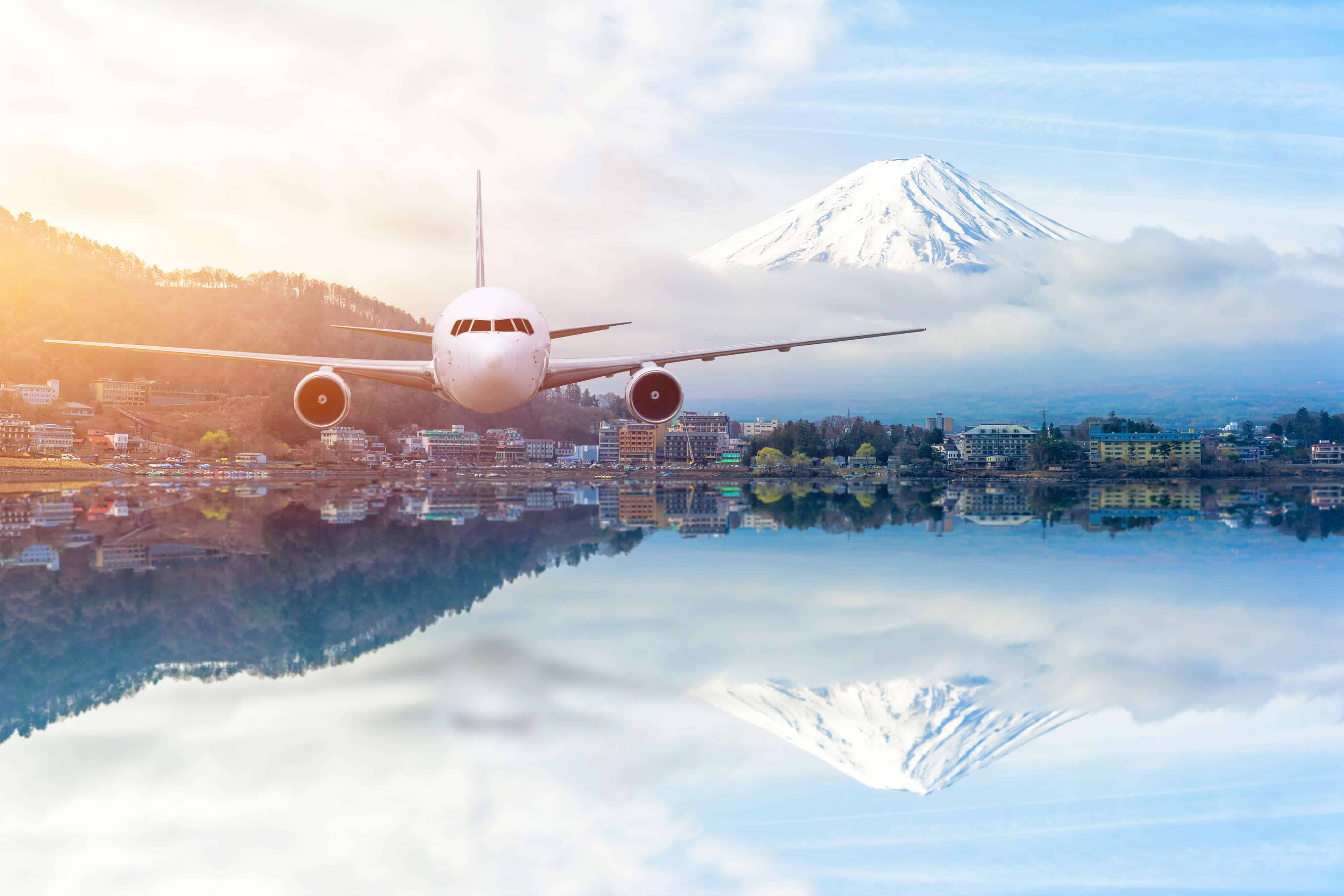 An illustratoin of a body of water with buildings around it. In the background is a snow-covered mountain, which is reflected on the surface of the water. Above this body of water is a airplane flying over it.
