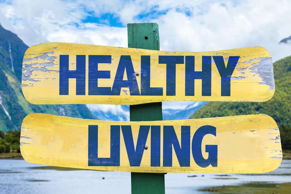 An illustration of a sign that reads, "HEALTHY LIVING." In the background a lake, mountains, and the sky can be seen.