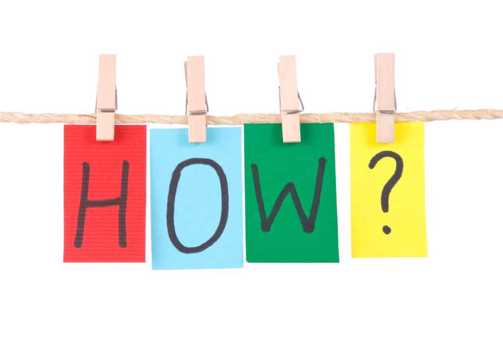The word "HOW?" spelled out with each letter on one piece of colored paper (red, light blue, green, and yellow, respectively) hanging from the clothesline with clothes pins.