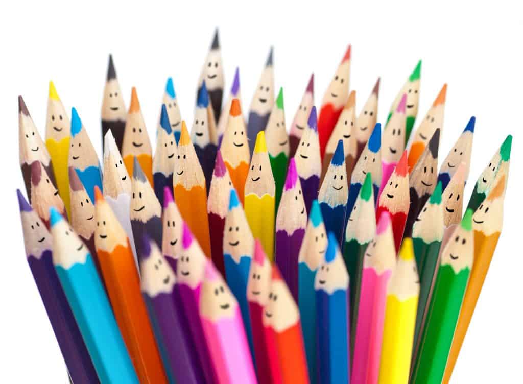 A big bunch of colored pencils, with a small happy face drawn on each of the tops. White background.