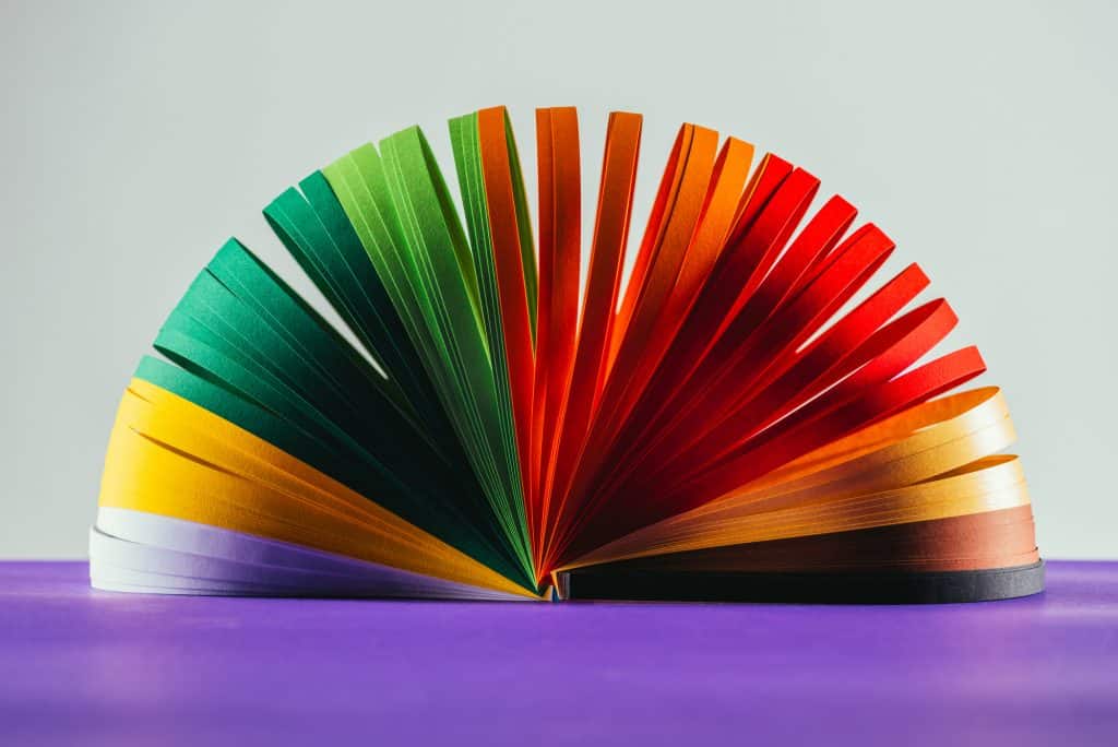 Strips of different colored pieces of paper (purple, yellow, green, red, orange, brown, black) stacked on top of each other to form a spiral shape (like a Slinky)