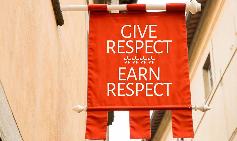 A red flag/cloth sign that is hanging from a pole that reads, "GIVE RESPECT EARN RESPECT."
