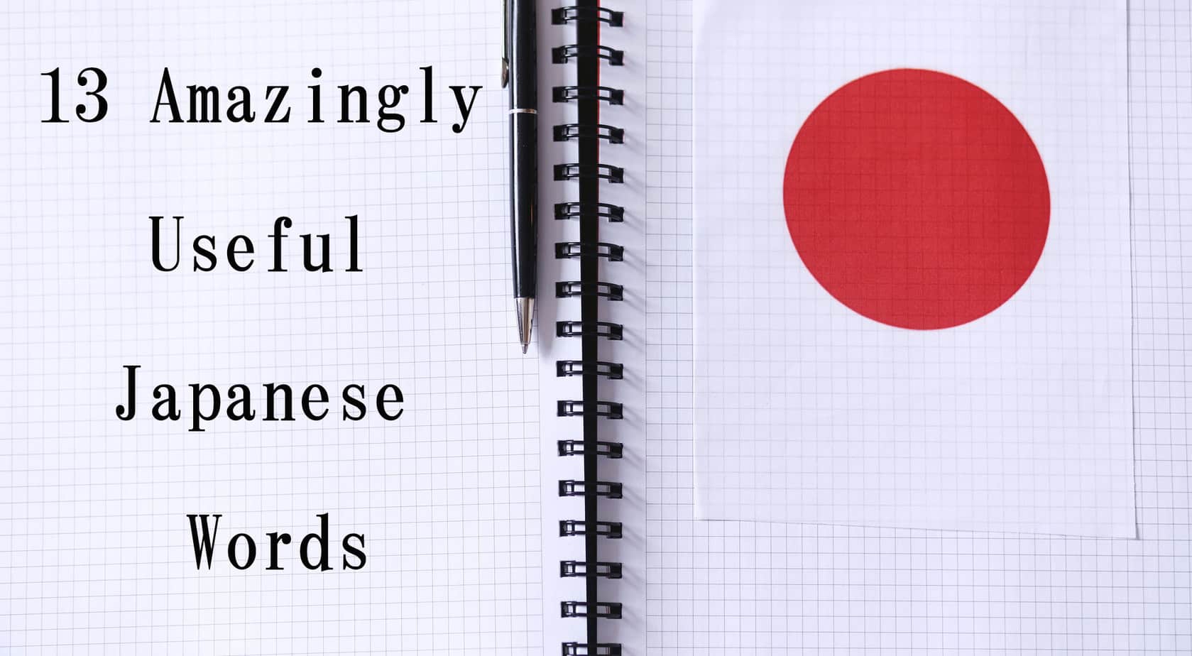 An open note book with a the text "13 Amazingly Useful Japanese Words" written on the left page, with a paper with a red circle on the right page. A pen is resting on top of the left page.