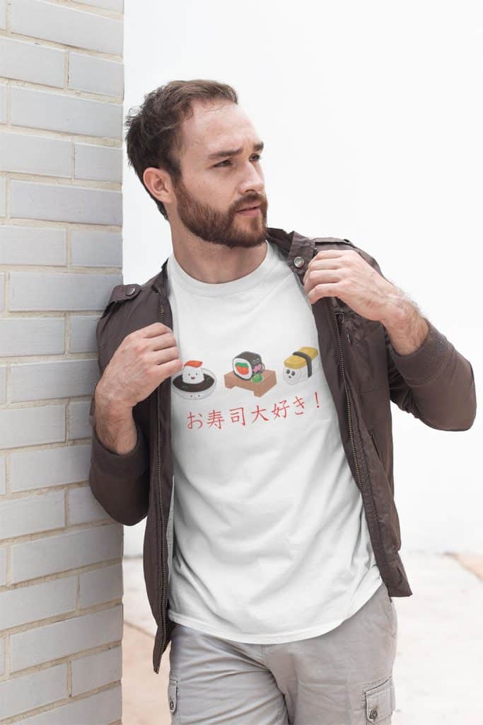 A young man with a beard and moustache wearing a brown jacket over a white shirt. The shit shirt has 3 cute sushi character illustrations on it, and Japanese text that translates to "I Love Sushi!"