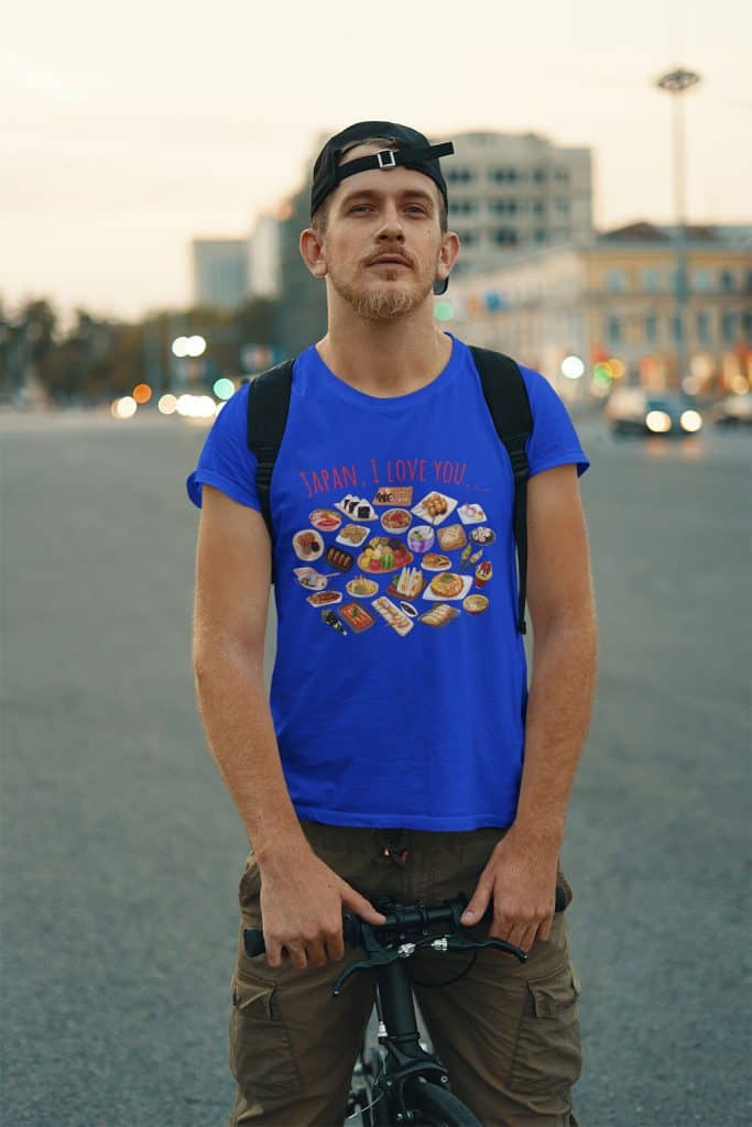 A young man with moustache on a bicycle, wearing a blue shirt that has illustrations of food from Japan. The English text on it reads, "JAPAN, I LOVE YOU..."