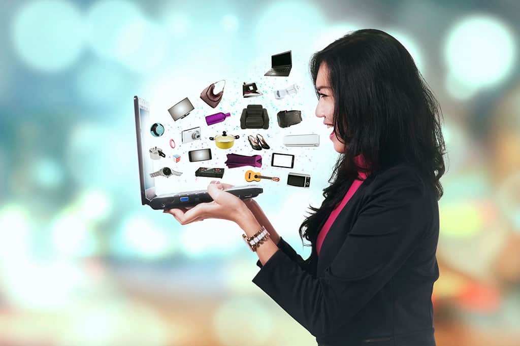 A woman holding a laptop. From the laptop, a lot of products (like a TV, watch, chair, etc.) is flying out (an illustration).