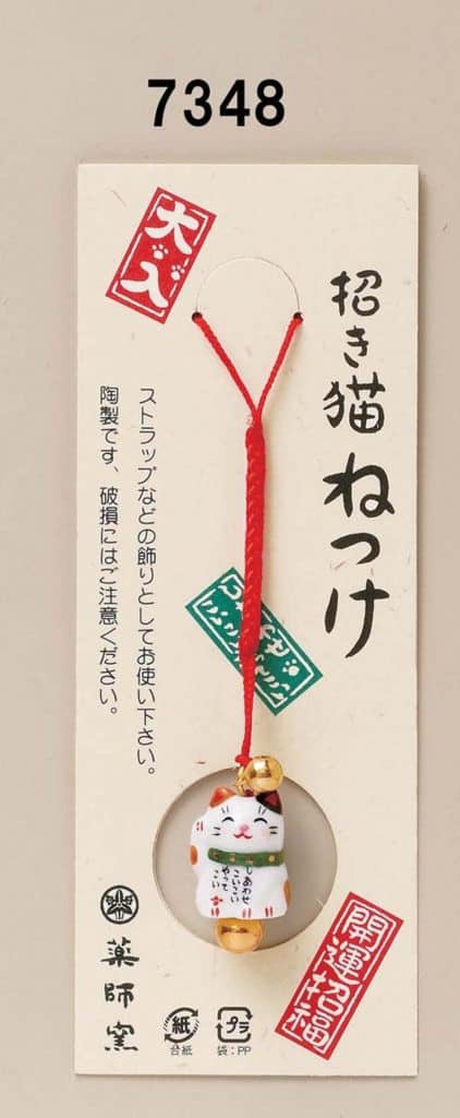 A small and cute Japanese lucky cat charm on a red strap.