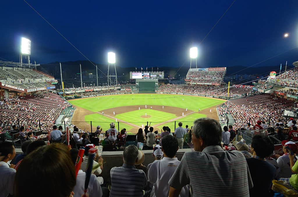 A baseball game with a full crowd at night at the Mazda Zoom Zoom Stadium in Hiroshima