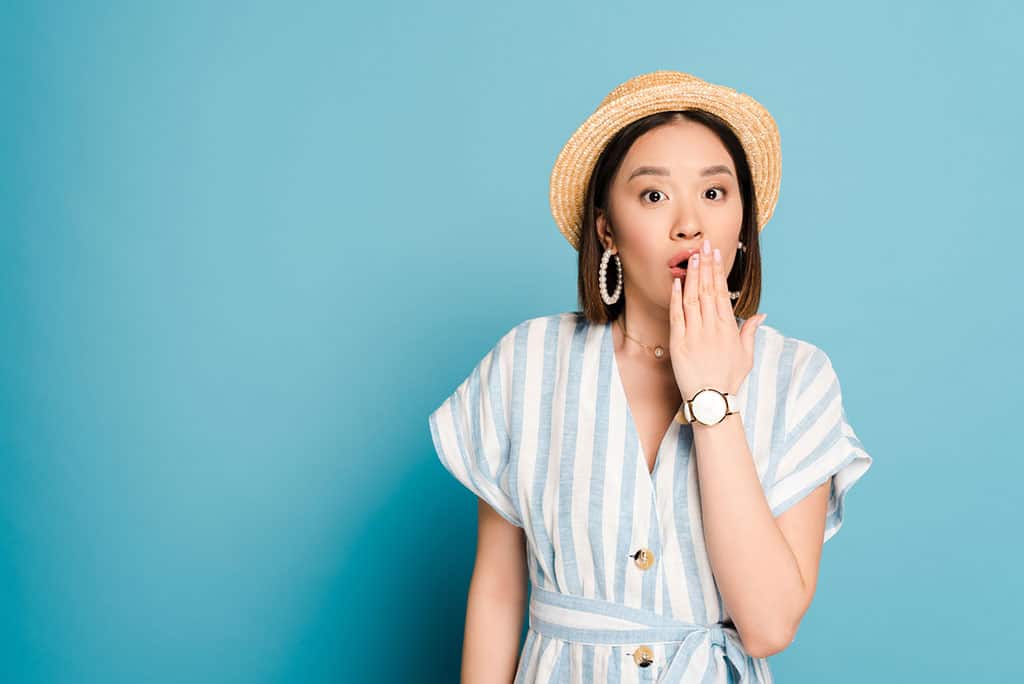 A young, Asian woman with her hand over her mouth looking a little shocked.