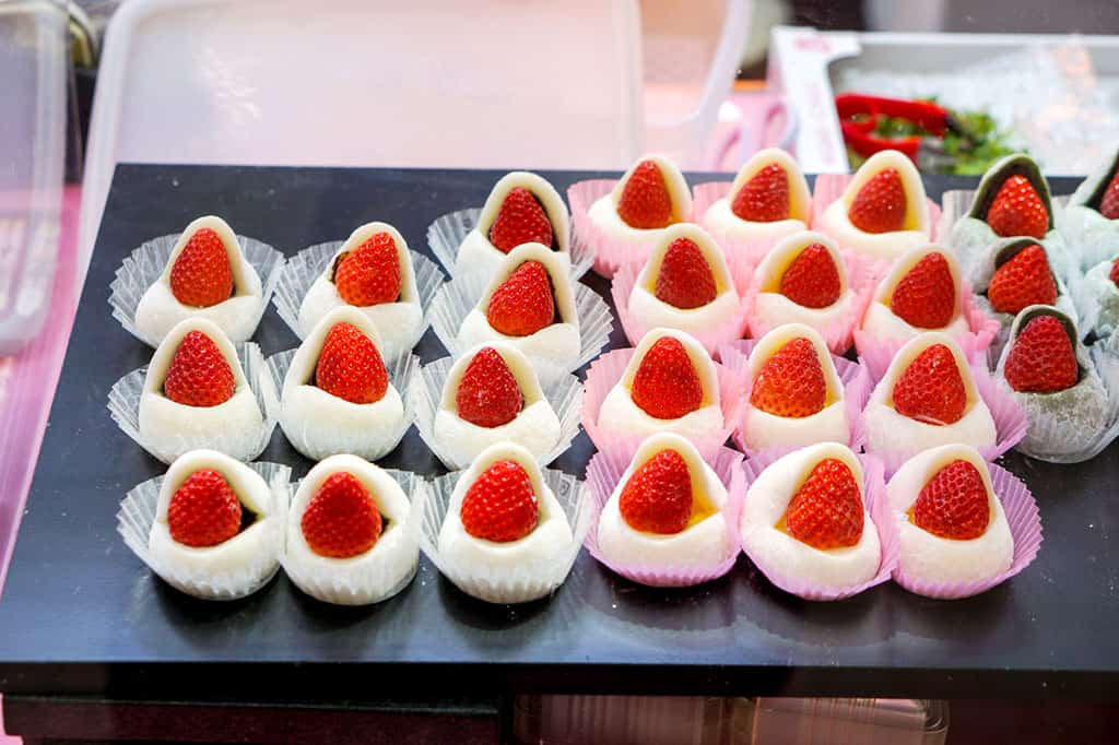 A display of ichigo daifuku, or strawberries with sweet bean paste in mochi in white and pink wrappers.